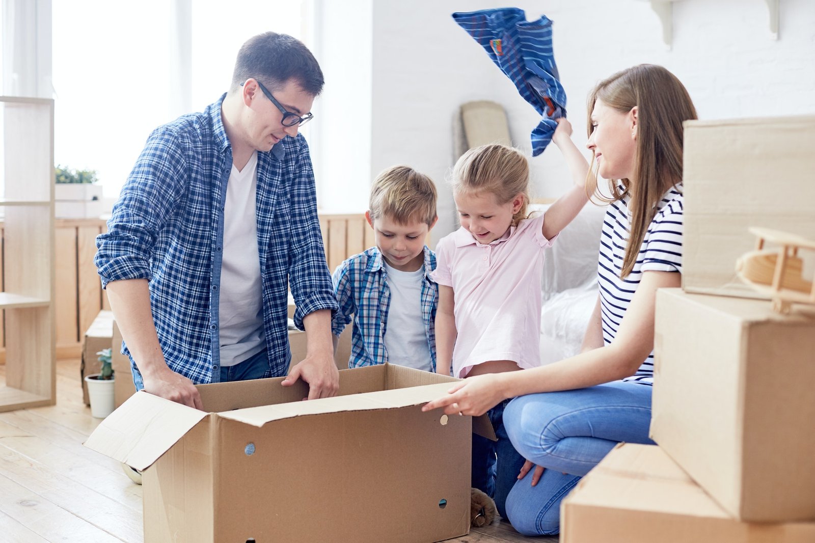 Self storage Castlebridge - Blackwater | Trusted Local Self storage 2 Happy family unpacking boxes in their new home, parents helping children unpack clothes. The children are excited, and the parents look content and joyful. Moving day excitement!