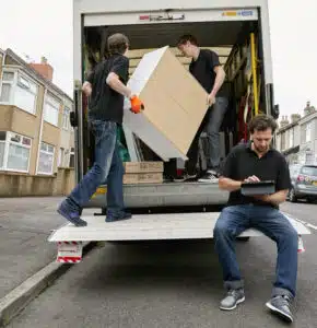 Removals business. A removals company, two men lifting furniture and one seated using a digital tablet. ,Moving Home with Removals Company, Ireland