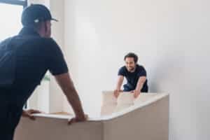 smiling worker moving white sofa with blurred coll 2024 11 07 22 57 38 utc