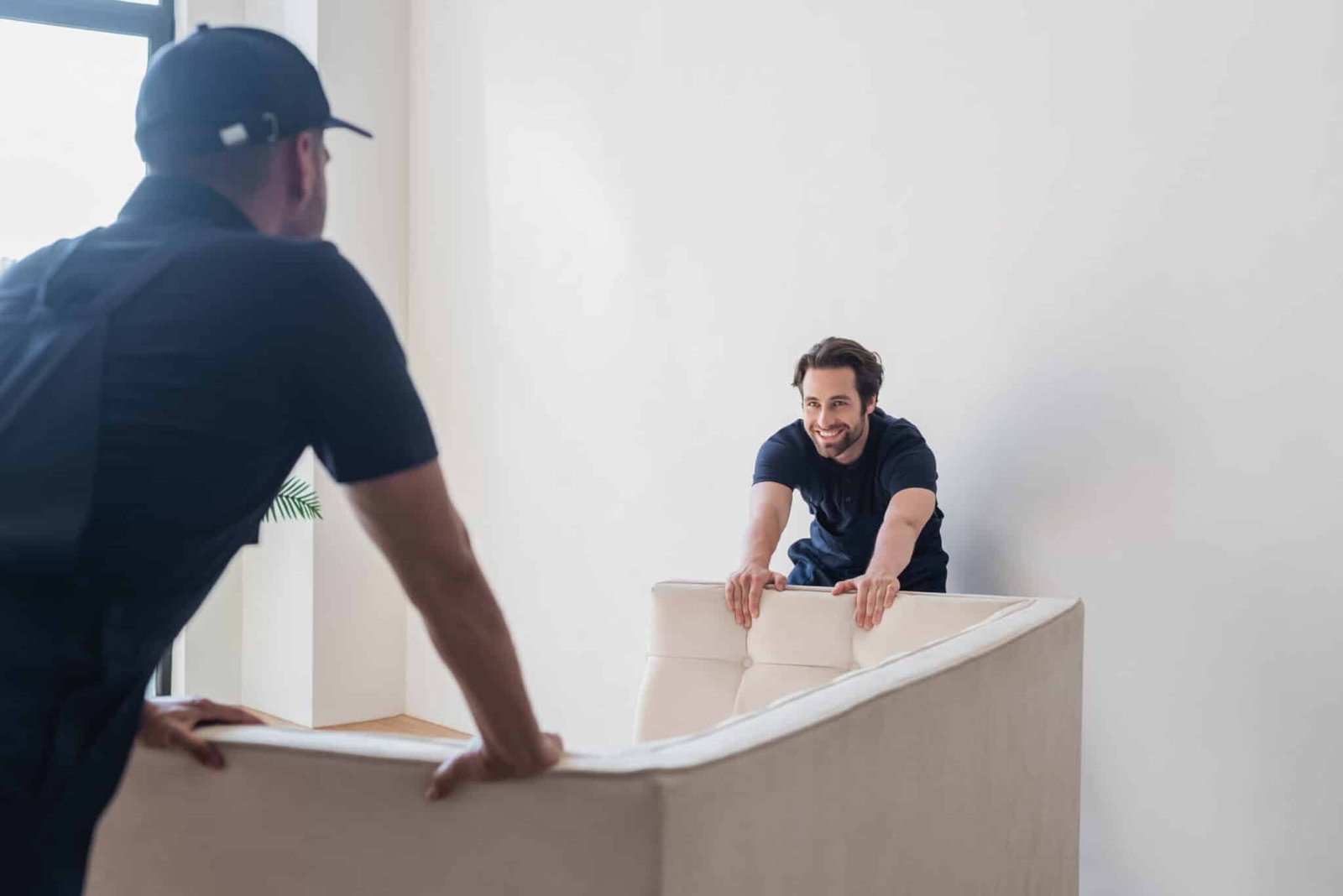 smiling worker moving white sofa with blurred coll 2024 11 07 22 57 38 utc scaled