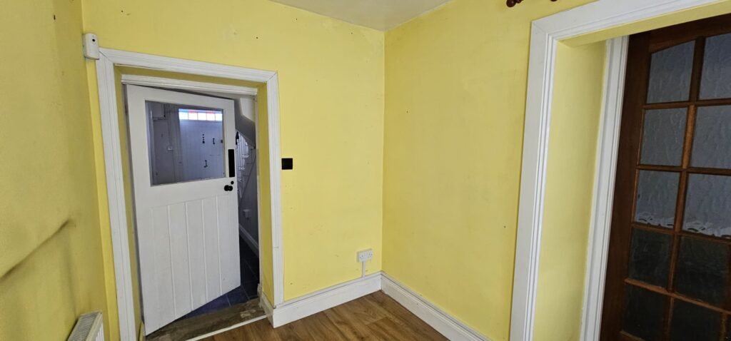 Interior of a room with bright yellow walls, white trim, and a partially open white door leading to another room. This scene is from a house featured in the Irish Independent, possibly being prepared for relocation by local movers.
