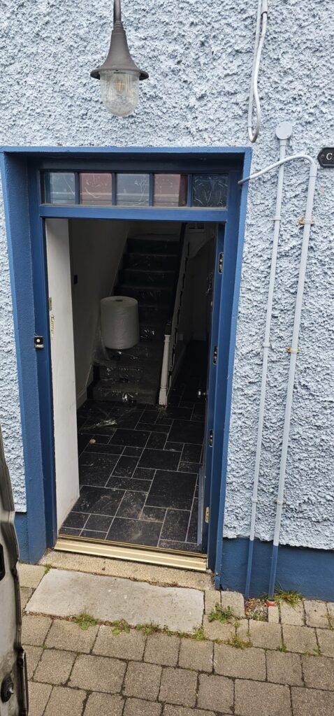 Blue-painted doorway of a house being moved by local movers, with bubble-wrapped stairs visible inside.