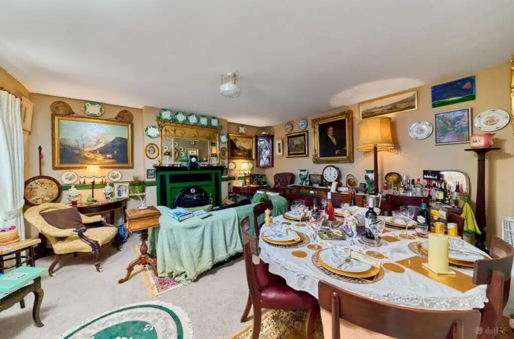 A cozy, cluttered living and dining room filled with antique furniture, artwork, and decorative plates, possibly a room from a house featured in the Irish Independent being prepared for local movers.