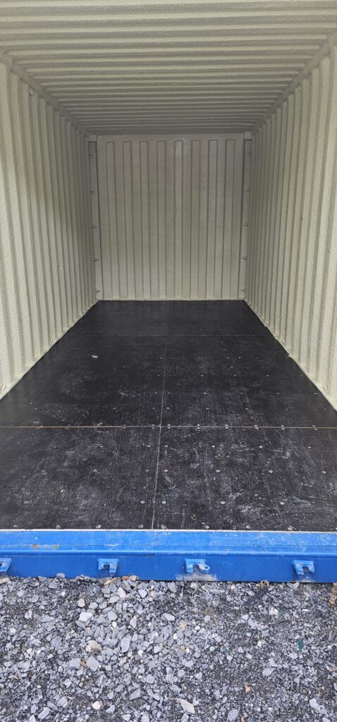 Inside of an empty shipping container with a dark wooden floor and ribbed, pale yellow walls, ready for moving from Dublin to Sligo.