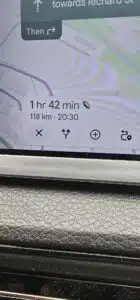 Navigation app on a car dashboard shows a 1 hr 42 min, 118 km trip to Richard St, with a leaf icon indicating an eco-friendly route.
