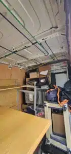 Interior view of a moving van packed with office supplies, furniture, and boxes, secured with colorful bungee cords and straps, ready for commercial relocation.