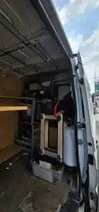 Interior of a white moving van packed with office furniture, boxes, and bubble wrap, ready for commercial relocation.