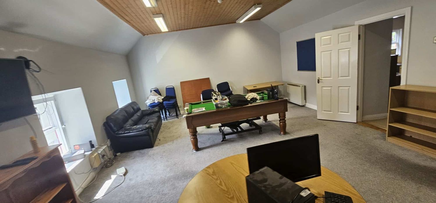 An empty office space with office furniture, including a desk, chairs, and a sofa, ready for commercial relocation by professional office movers.