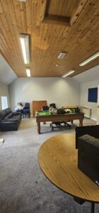 Empty office space with a pool table, couch, and desks, showcasing a commercial relocation by office movers.