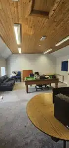 Empty office space with a pool table, couch, and desks, showcasing a commercial relocation by office movers.